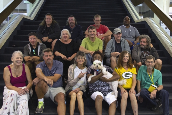 A group of people sit on a set of stairs, smiling at the camera.